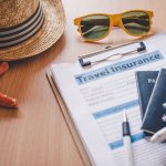 chapeau lunettes de soleil passeport et stylo posés sur un formulaire assurance voyage