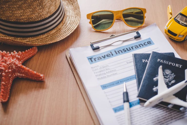 chapeau lunettes de soleil passeport et stylo posés sur un formulaire assurance voyage